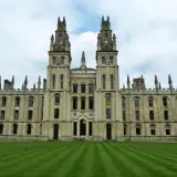 Imponująca architektura **Oxford uczelnia** z dwoma wieżami i zadbanym trawnikiem.
