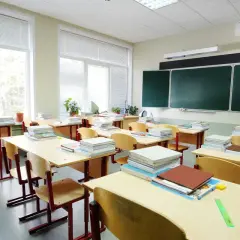 Puste ławki i stosy książek w sali lekcyjnej, jakby właśnie skończył się rok szkolny.
