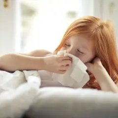 Ruda dziewczynka w łóżku z chusteczką przy nosie. Chyba zasłużyła na zwolnienie z wf.