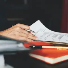 Ręka trzymająca długopis nad dokumentem z napisem "RESUME". To idealny moment na dopracowanie swojego CV po angielsku.