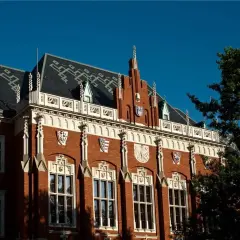 Elegancka fasada jednego z uniwersytetów w Krakowie, z charakterystycznymi detalami architektonicznymi i herbami.