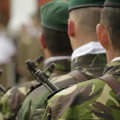 Żołnierze w mundurach i zielonych beretach, z karabinami, przygotowują się do uroczystości. To ich studia oficerskie.