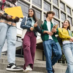Grupa studentów schodzi po schodach, niosąc książki i teczki. Ich uśmiechy sugerują, że są gotowi na wyzwania, niczym w ramach obrony cywilnej.