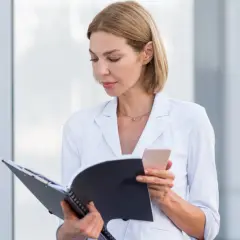 Koordynator medyczny w białej marynarce przegląda dokumenty i sprawdza telefon.