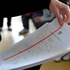Dłoń trzyma stos świadectw szkolnych. Czy religia wlicza się do średniej? Ważne dokumenty edukacyjne.