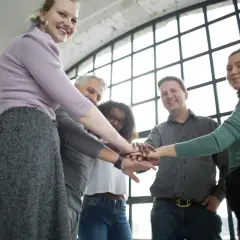 Zespół ludzi zjednoczony w geście wsparcia, gotowy do podjęcia wyzwań. Ich wspólne wysiłki w ramach resocjalizacja studia przyniosą pozytywne zmiany.
