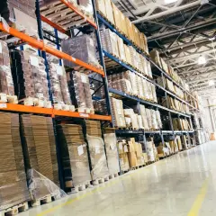 Wielkie regały magazynowe pełne paczek i palet, idealne do studiów logistycznych.