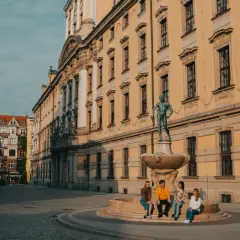 Studenci na wrocławskim Rynku, marzący o doktoracie. Słoneczny dzień, zabytkowa architektura.