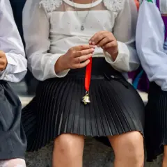 Dzieci w szkolnych strojach, jedno trzyma dzwoneczek na czerwonej wstążce. Od jakiej średniej jest pasek?
