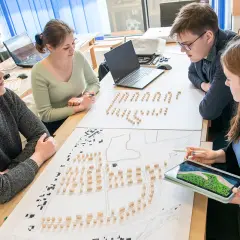 Studenci architektury analizują projekt urbanistyczny z makietą i planami.