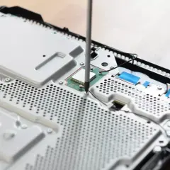 Uczeń technikum podczas praktyk zawodowych skręca konsolę.