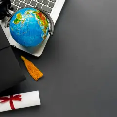 Dyplom, czapka absolwenta i globus na laptopie symbolizują globalne wykształcenie i nostryfikację.