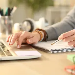 Studentka pisze notatki i pracuje na laptopie, zgłębiając tajniki filologii polskiej.
