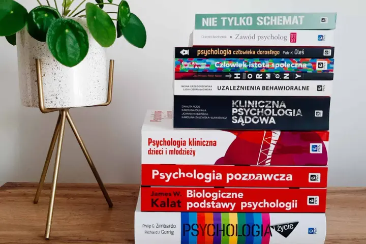 Stos książek do psychologii klinicznej studiów, w tym "Psychologia kliniczna dzieci i młodzieży" i "Psychologia sądowa", obok rośliny w doniczce.