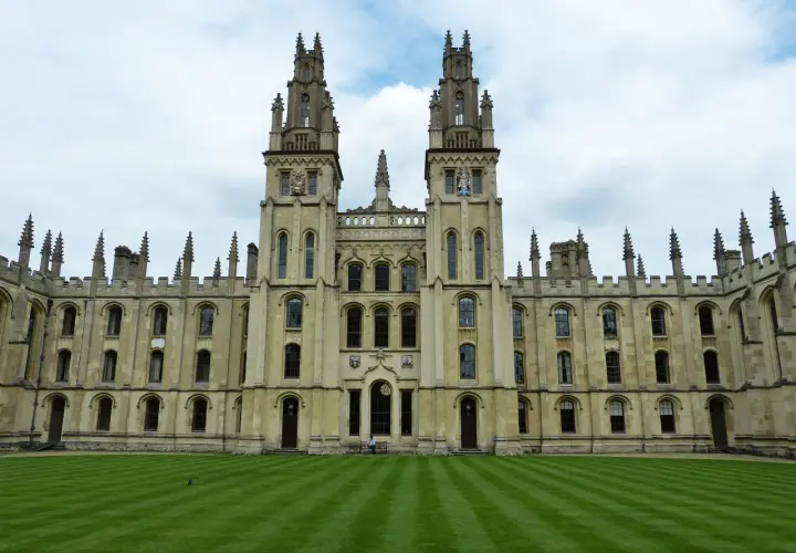 Imponująca architektura **Oxford uczelnia** z dwoma wieżami i zadbanym trawnikiem.