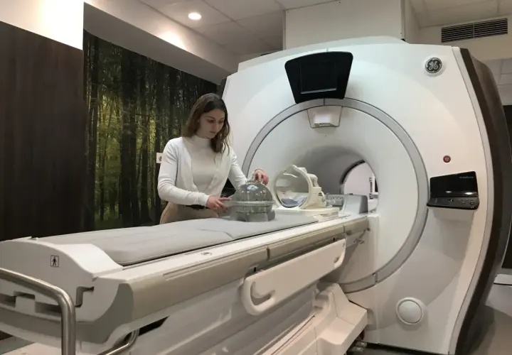 Kobieta przy aparacie MRI, przygotowująca fantom do badań. Praca w dziedzinie fizyki medycznej.