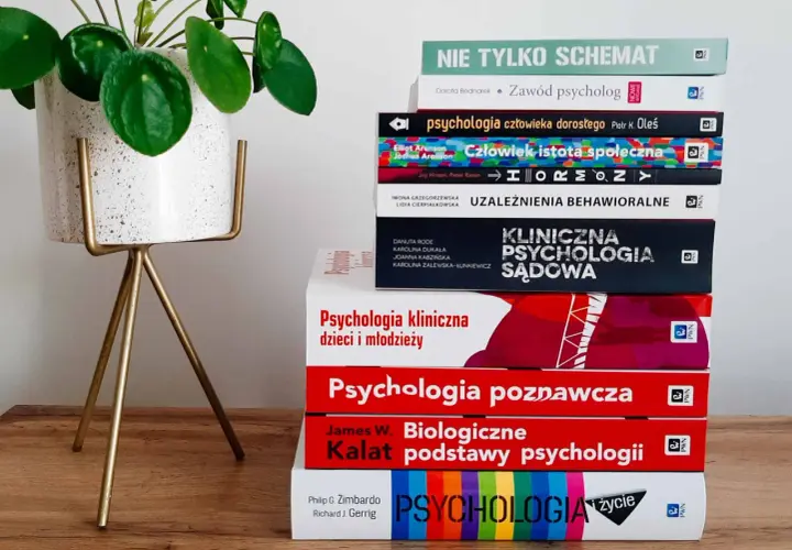 Stos książek do psychologii klinicznej studiów, w tym "Psychologia kliniczna dzieci i młodzieży" i "Psychologia sądowa", obok rośliny w doniczce.