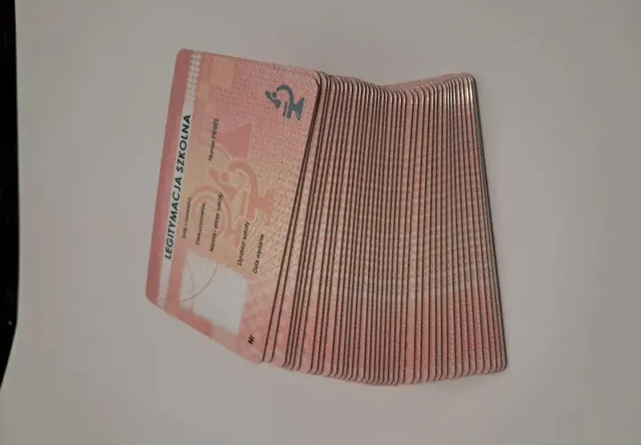 Stos szkolnych legitymacji, ważnych dokumentów potwierdzających tożsamość ucznia. Każde świadectwo jest gotowe do odbioru.