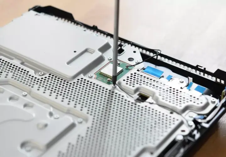 Uczeń technikum podczas praktyk zawodowych skręca konsolę.