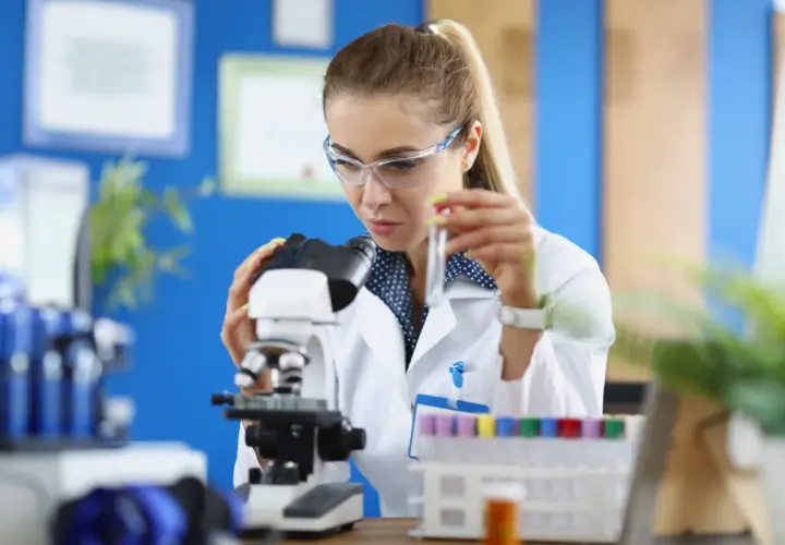 Studentka na biotechnologia studia bada próbkę pod mikroskopem.
