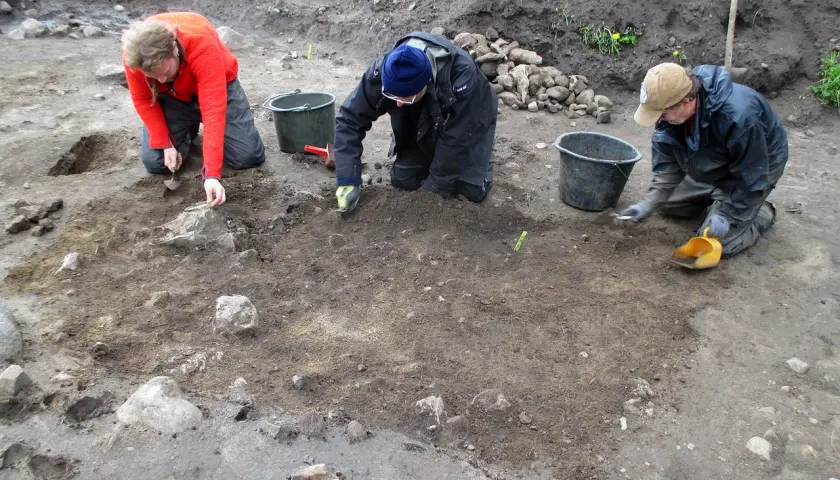 Osoby prowadzą archeologia studia, ostrożnie badając ziemię i kamienie.