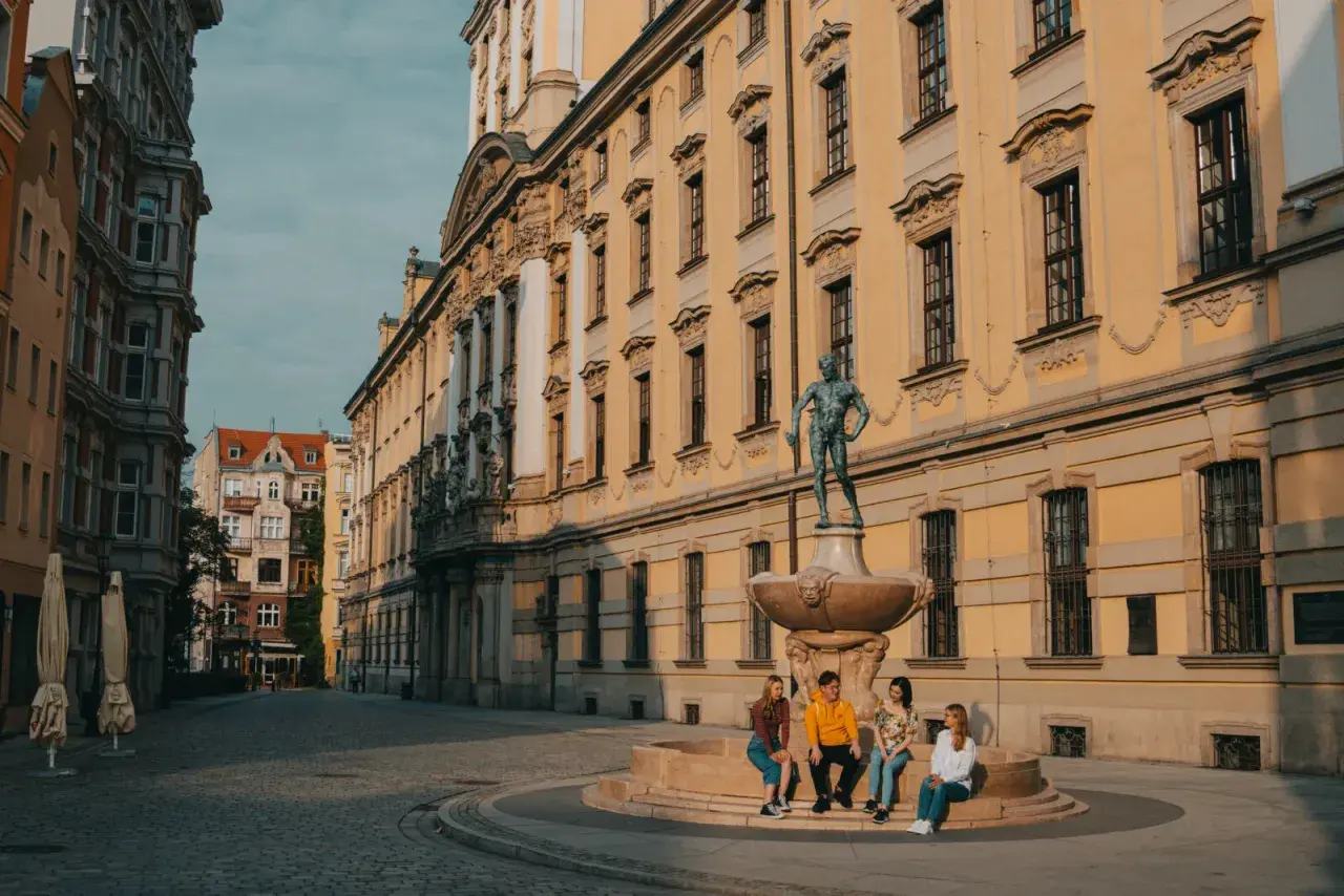 Studenci na wrocławskim Rynku, marzący o doktoracie. Słoneczny dzień, zabytkowa architektura.