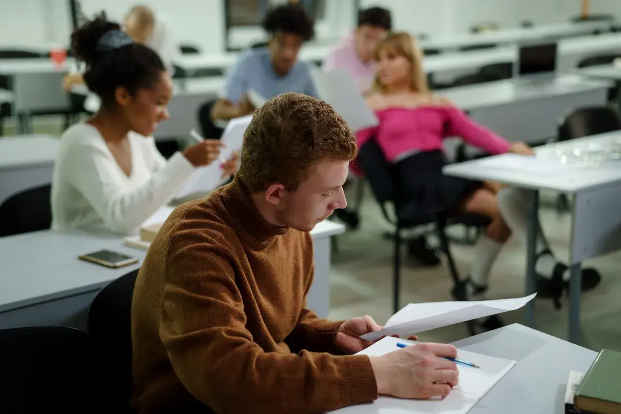 Studenci w sali wykładowej, skupieni na nauce. Nawet bez matury można rozpocząć studia, zdobywając wiedzę i nowe umiejętności.