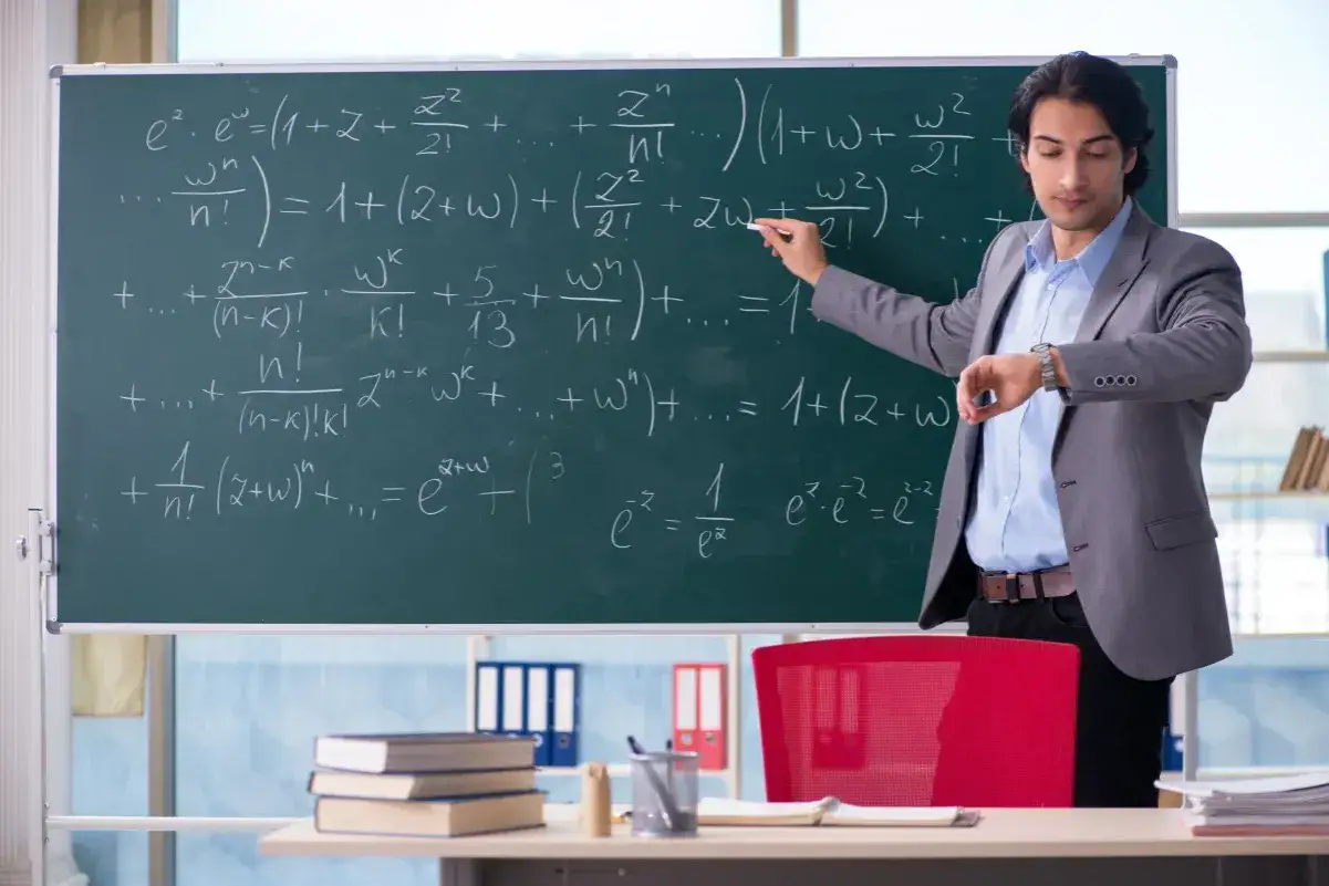 Nauczyciel matematyki tłumaczy skomplikowane wzory na tablicy, sprawdzając jednocześnie zegarek. Jego etat wymaga precyzji i cierpliwości.