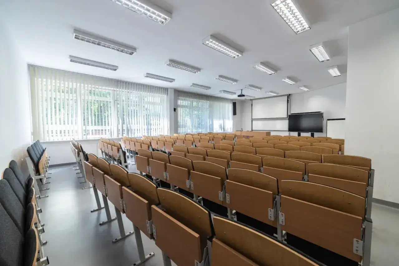 Pusta sala wykładowa z rzędami drewnianych ławek, idealna na studia magisterskie.