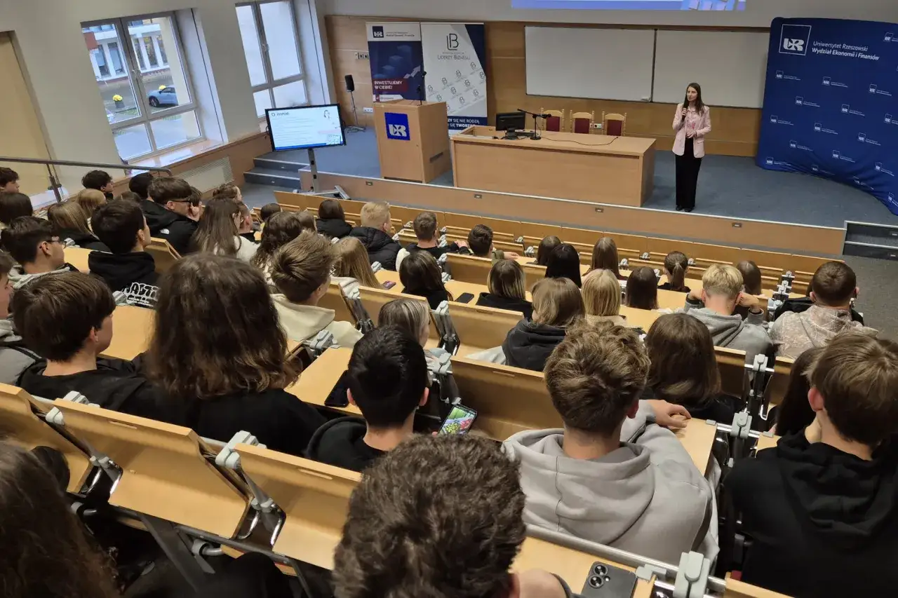 Wykład na studiach ekonomicznych. Młodzi ludzie słuchają prelegentki w auli uniwersyteckiej.