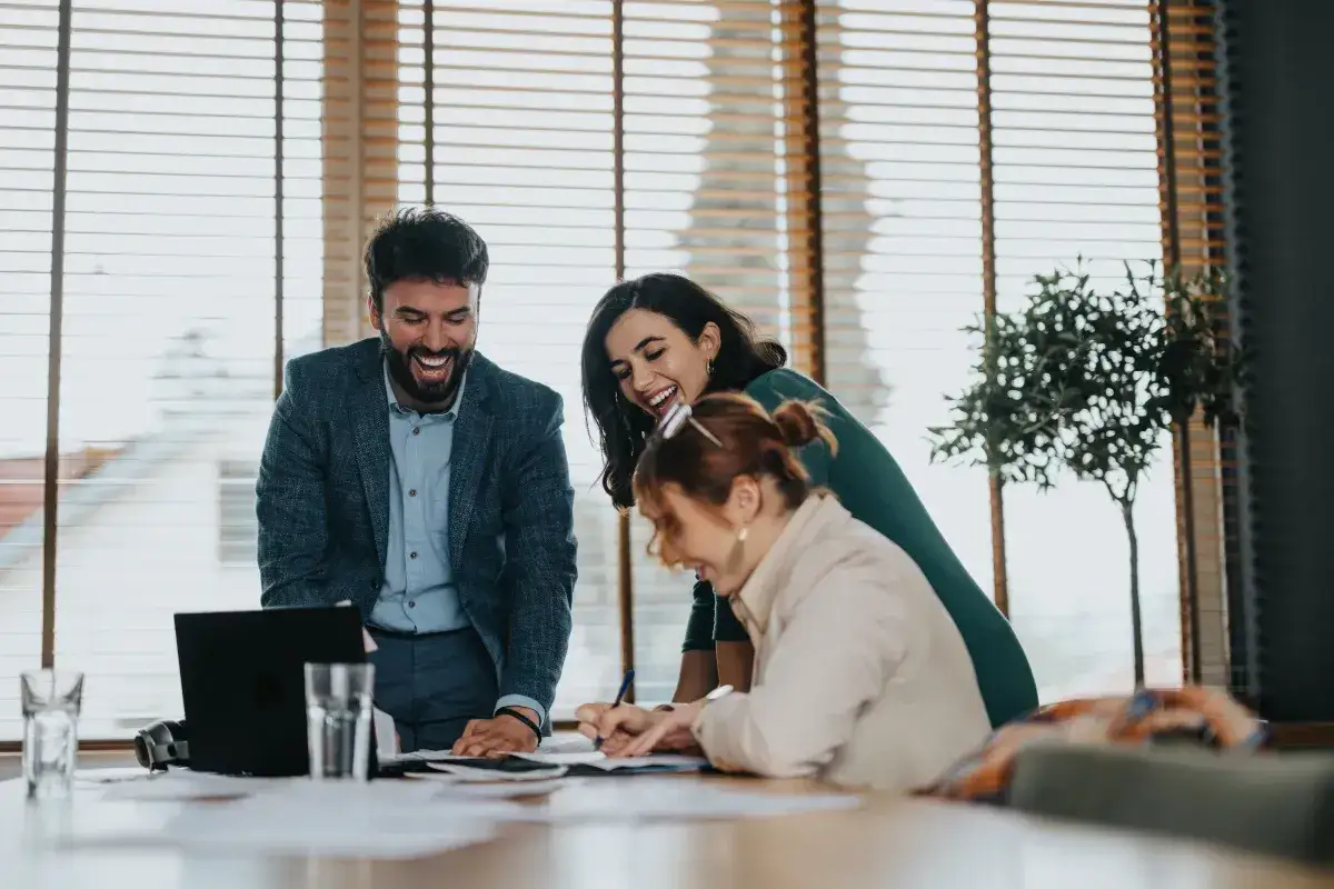 Uśmiechnięty akwizytor z zespołem śmieje się podczas spotkania przy laptopie.